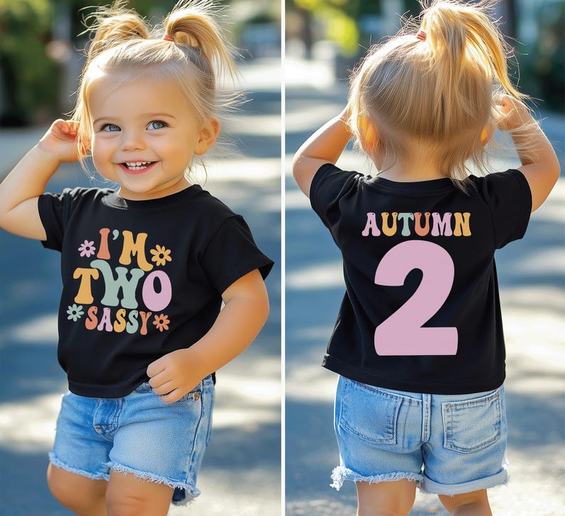 Może przedstawiać: Czarny t-shirt z kolorową grafiką, na kt&oacute;rej z przodu widnieje napis "I'm Two Sassy", a z tyłu "Autumn 2". Koszulkę nosi małe dziecko.