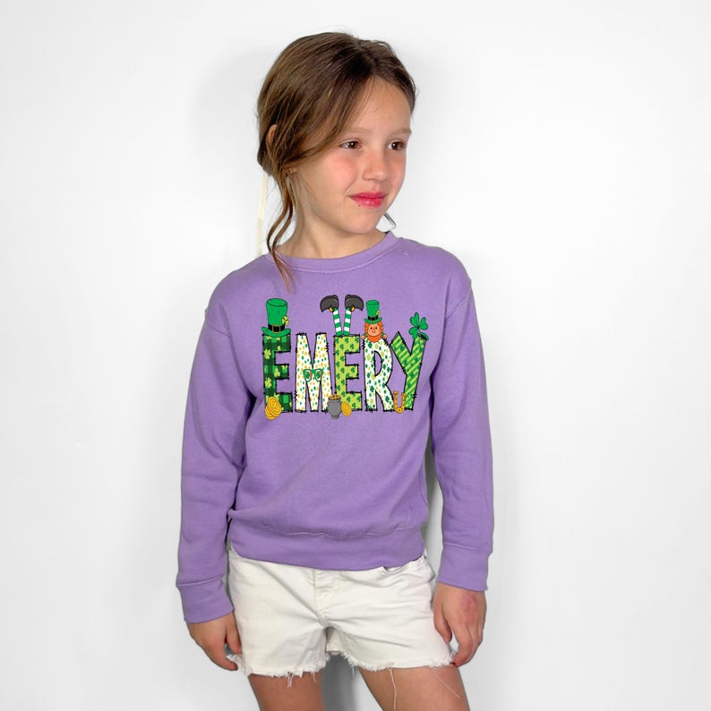 May include: A purple sweatshirt with a green, yellow, and orange design that says "EMERY" with leprechauns and shamrocks.