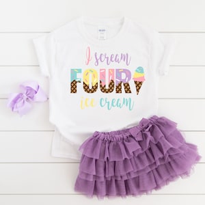 Puede incluir: Camiseta blanca con el texto "I scream four ice cream" en letras de colores con gr&aacute;ficos de conos de helado. La camiseta se combina con una falda de tul morada.