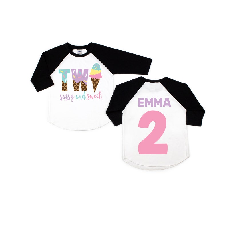 Pu&ograve; includere: Due magliette da baseball a tema cono gelato. La parte anteriore di una maglietta dice "Two sassy and sweet" con una grafica di cono gelato. La parte posteriore dell'altra maglietta dice "Emma 2" in rosa.