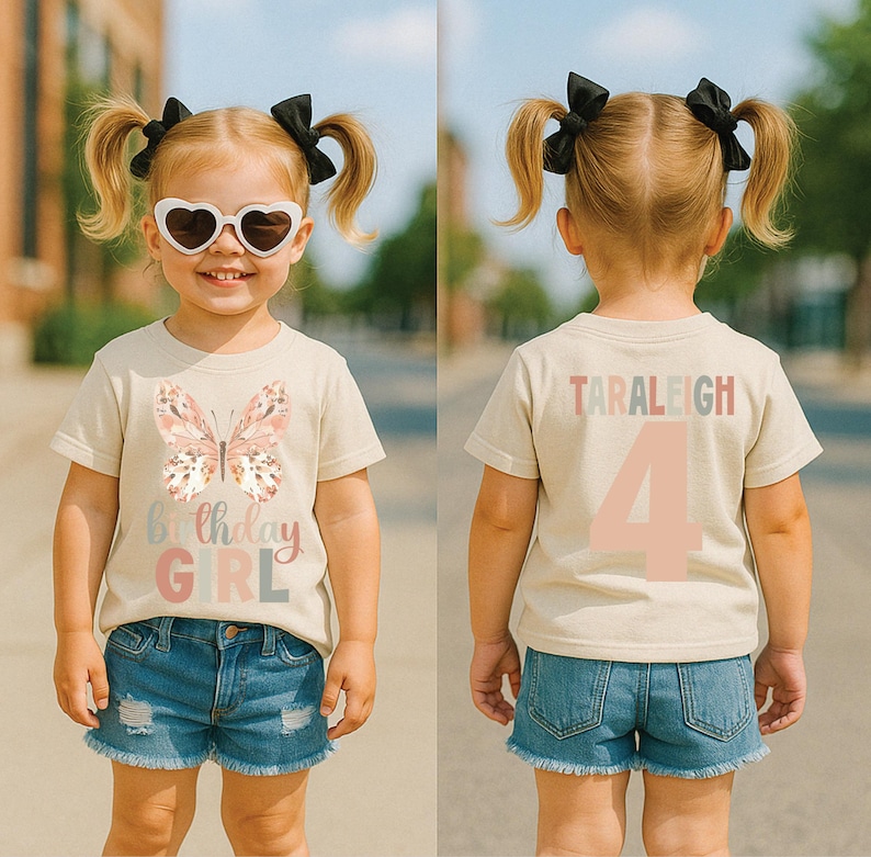 May include: A beige t-shirt featuring a butterfly design and the words "Birthday GIRL" in pastel shades. The back of the shirt displays the name "TARALEIGH" and the number "4". The child is wearing denim shorts and heart-shaped sunglasses.