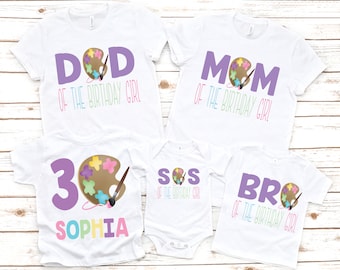 May include: A set of four white t-shirts with a paint palette and paintbrush design. The shirts say "Dad of the Birthday Girl", "Mom of the Birthday Girl", "Sis of the Birthday Girl", and "Bro of the Birthday Girl". One shirt also has the number "3" and the name "Sophia" on it.