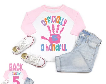 May include: A white and pink baseball tee shirt with a rainbow handprint and the text "Officially a handful" with the number 5 inside the handprint. The back of the shirt has the name Avery and the number 5 in pink.