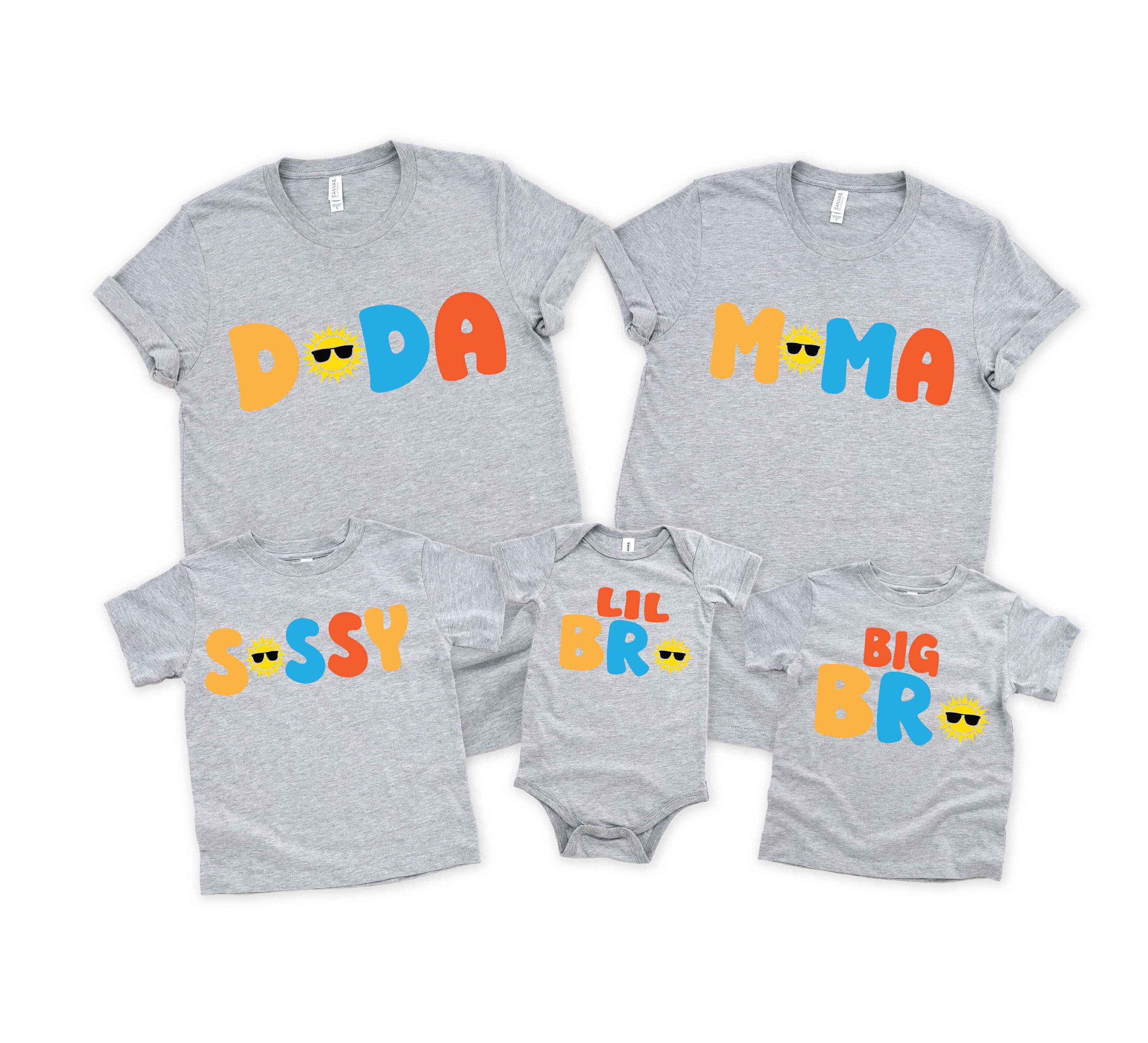 May include: Five heather grey garments including two adult t-shirts, two children's t-shirts, and one infant bodysuit. The shirts feature colourful text: DADA, MAMA, SISSY, LIL BRO, and BIG BRO, with yellow sun icons wearing black sunglasses.