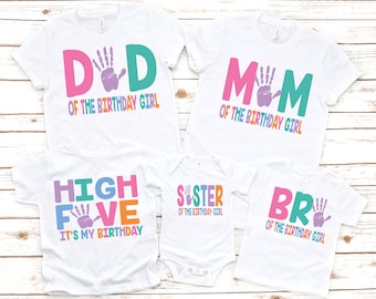 May include: A set of five white t-shirts with colorful text and handprint designs. The shirts say "Dad of the Birthday Girl", "Mom of the Birthday Girl", "High Five It's My Birthday", "Sister of the Birthday Girl", and "Bro of the Birthday Girl".
