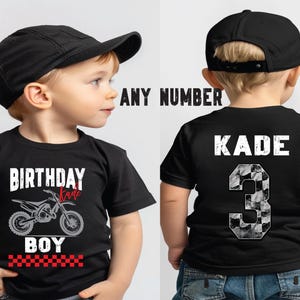 Puede incluir: Camiseta negra con un gr&aacute;fico de motocicleta y las palabras "BIRTHAY BOY" en blanco. La palabra "Kade" y el n&uacute;mero "3" est&aacute;n en la espalda. El n&uacute;mero tiene un patr&oacute;n de cuadros. El ni&ntilde;o lleva una gorra de b&eacute;isbol negra.