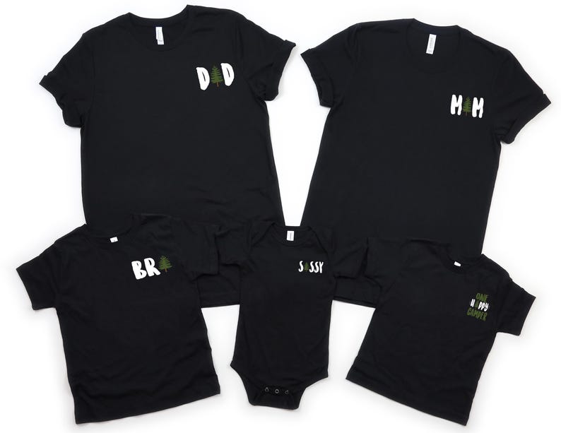 Puede incluir: Camisetas negras y un body negro con texto blanco y gr&aacute;ficos de &aacute;rboles verdes. Las camisetas tienen el texto "DAD", "MOM", "BR" y "CAMP HAPPY CAMPER". El body tiene el texto "SASSY".