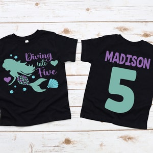 May include: Two black t-shirts with a mermaid design and the text "Diving into Five" on the front and the name "MADISON" and the number "5" on the back.