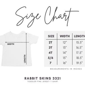 May include: A white toddler fine jersey t-shirt, Rabbit Skins 3321, with a size chart displaying width and length measurements in inches for sizes 2T through 7. The chart lists specific dimensions for each size, ranging from 12 to 16 inches in width and 15.5 to 19.5 inches in length.