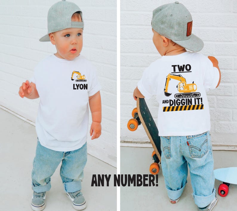 May include: A white t-shirt featuring a yellow excavator graphic and the name LYON on the front, with a larger yellow excavator graphic, the text TWO AND DIGGIN IT!, and a black and yellow caution stripe pattern printed on the back of the shirt.