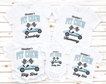 以下が含まれることがあります： レーシングテーマの白いTシャツとボディスーツ。各シャツには、ライトブルーのレーシングカーのグラフィックと「Daddy」、「Mommy」、「Big Bro」、「Baby Bro」という言葉の上に「Kaiden's PIT CREW」というテキストが表示されています。