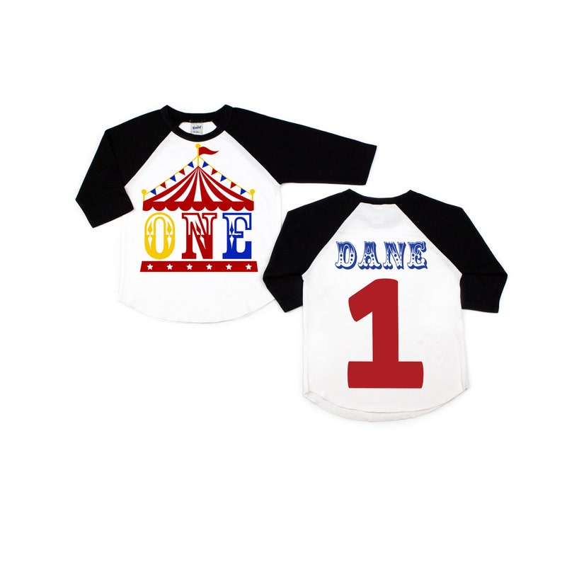 Puede incluir: Dos camisetas de b&eacute;isbol blancas y negras con un gr&aacute;fico de carpa de circo roja y amarilla en la parte delantera. Una camiseta dice "ONE" y la otra dice "DANE 1".