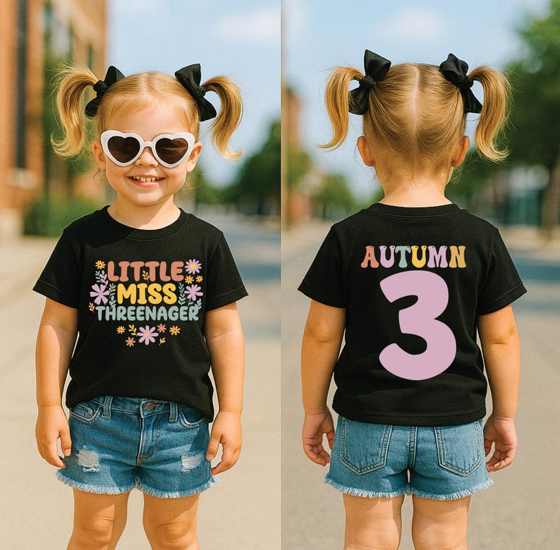 May include: A black short-sleeve t-shirt featuring the text 'LITTLE MISS THREENAGER' with colorful flower graphics on the front and the name 'AUTUMN' above a large number '3' in light pink on the back, paired with blue denim shorts.