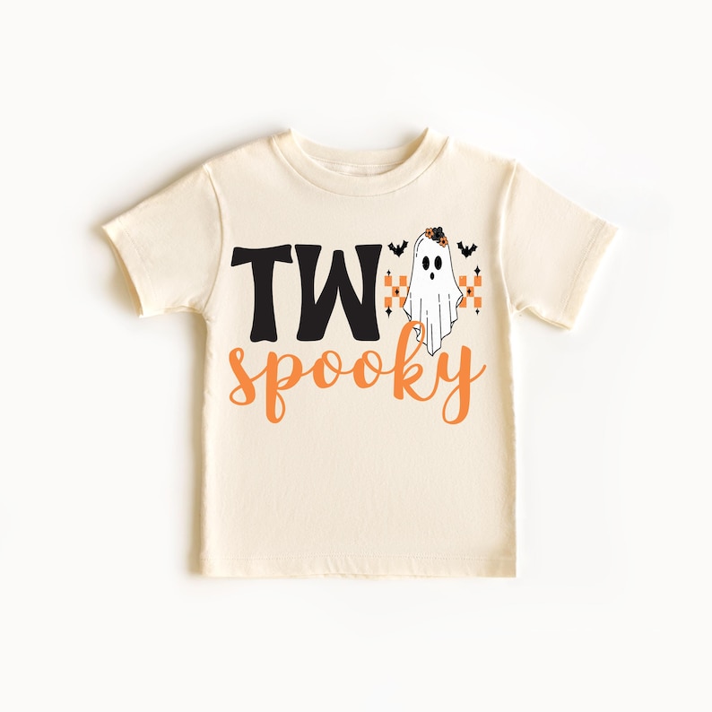 Pu&ograve; includere: T-shirt color crema per bambini piccoli con le parole "TW" in nero e "spooky" in arancione. Un fantasma dei cartoni animati con una fascia floreale e pipistrelli &egrave; stampato sulla maglietta, perfetto per Halloween.