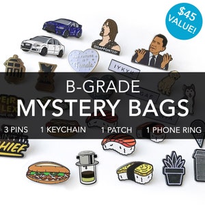 May include: A collection of enamel pins, a keychain, a patch, and a phone ring in a mystery bag. The bag contains a variety of themes, including cars, food, and pop culture references. The text on the bag reads "B-Grade Mystery Bags".