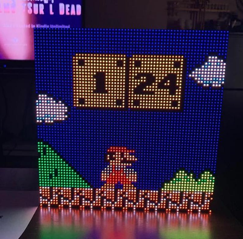May include: A pixelated LED light display depicting a scene from Super Mario Bros. The display shows Mario, a timer reading 1:24, clouds, and a green and brown landscape against a blue backdrop.