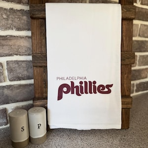 May include: White kitchen towel with the words "PHILADELPHIA PHILLIES" in maroon lettering.