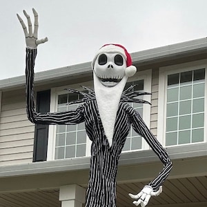 May include: A large outdoor decoration of Jack Skellington from The Nightmare Before Christmas. The figure is wearing a black and white striped suit and a Santa hat. The figure has a long, white neck and a skeletal face.