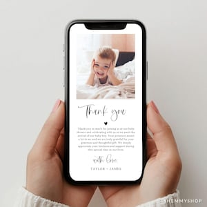 May include: A smartphone displays a baby shower thank you card. The card features a photo of a smiling child, the words "Thank you" in elegant script, and a heartfelt message. The card is held in a person's hands.