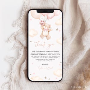 以下が含まれることがあります： スマートフォンに表示されたベビーシャワーのサンキューカード。カードには、風船を持ったテディベアのイラストが描かれています。「thank you」の文字は筆記体で書かれており、下にテキストが追加されています。