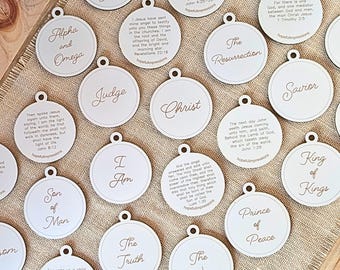 May include: A set of 15 round wooden ornaments with various Christian titles and scripture verses. The ornaments are white with brown text.