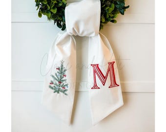 May include: White fabric Christmas stocking with a green embroidered Christmas tree on one side and a red embroidered letter "M" on the other side.
