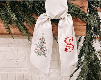 May include: White satin ribbon with a red embroidered Christmas tree on one side and a red embroidered letter "S" on the other side.