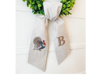 May include: A white fabric door swag with an embroidered turkey and the letter "B".