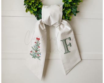 May include: White fabric Christmas stocking with a green embroidered Christmas tree on one side and the letter "F" on the other side.