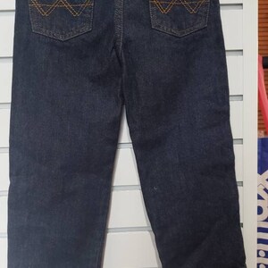 May include: Dark blue denim jeans with a pink lace waistband and brown stitching on the back pockets.