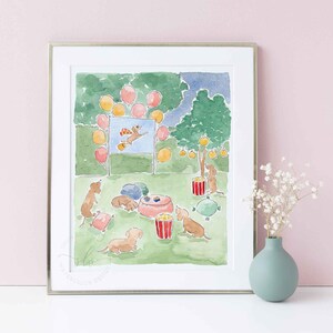 May include: Watercolour print depicting a dog party. The artwork shows dachshunds, balloons, popcorn, and a dog-themed movie screen. The scene is set in a park with a green lawn and trees. The print is framed in a silver frame.