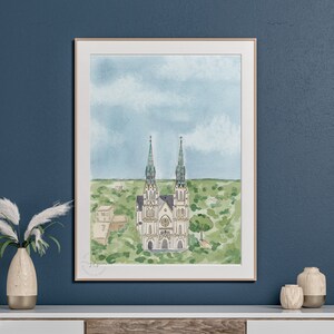 May include: A watercolor painting of a white church with two tall spires and green roofs. The church is surrounded by green trees and bushes. The sky is blue with white clouds.
