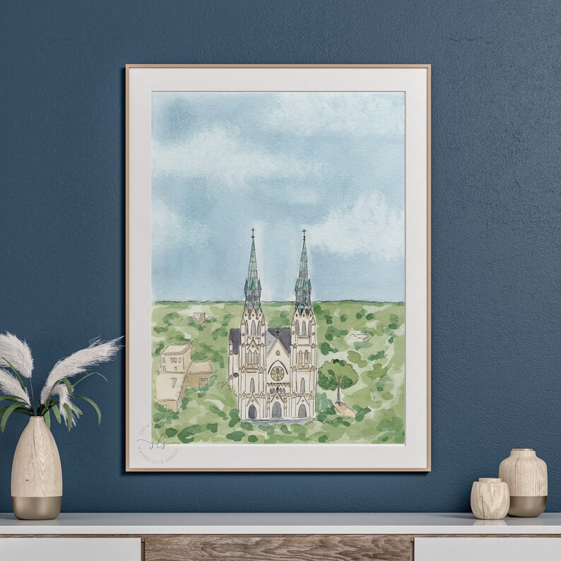 May include: A watercolor painting of a white church with two tall spires and green roofs. The church is surrounded by green trees and bushes. The sky is blue with white clouds.