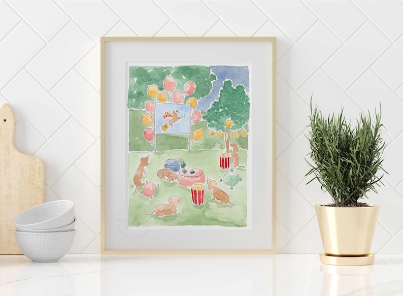 May include: Watercolour print depicting a dog party. Dachshunds are gathered around a pink bowl, with balloons and a movie screen. The artwork is framed in a light wood frame and set against a white tile background.