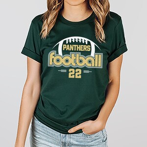 May include: A green t-shirt with a gold and white graphic that says "Panthers Football 22".