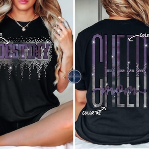May include: Black t-shirts with rhinestone designs. One shirt features the word "DESTINY" in purple and silver rhinestones. The other shirt has "CHEER MOM" in purple and silver rhinestones on the back. Both shirts are short-sleeved.
