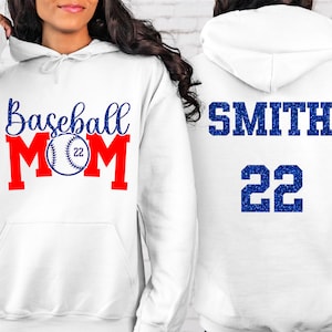 May include: White hoodie with the text "Baseball Mom" in blue and red with a baseball graphic. The back of the hoodie has the text "SMITH 22" in blue.