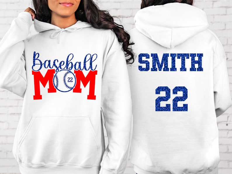 May include: White hoodie with the text "Baseball Mom" in blue and red with a baseball graphic. The back of the hoodie has the text "SMITH 22" in blue.
