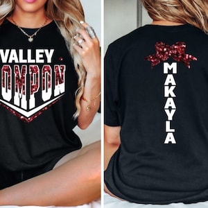 May include: Black t-shirt with a white design that says "Valley Pompon" with red glitter accents. The back of the shirt has a red glitter bow with the name "Makayla" written vertically in white.