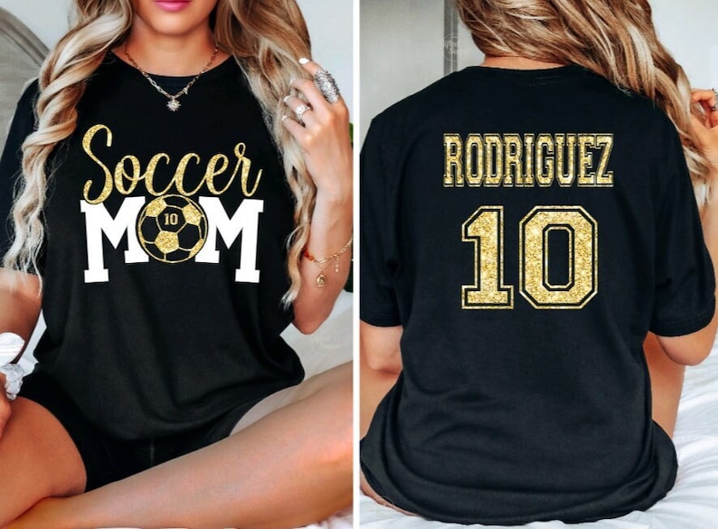 Op de afbeelding: Zwart T-shirt met gouden glittertekst die "Soccer Mom" zegt en een voetbal met nummer 10 erop. De achterkant van het shirt heeft gouden glittertekst die "Rodriguez" zegt en nummer 10.