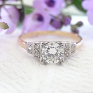 May include: A vintage engagement ring with a large, round, brilliant-cut diamond set in a platinum setting. The band is made of 14k yellow gold.