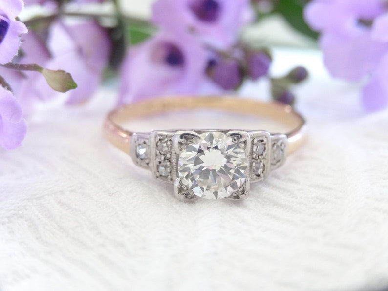 May include: A vintage engagement ring with a large, round, brilliant-cut diamond set in a platinum setting. The band is made of 14k yellow gold.