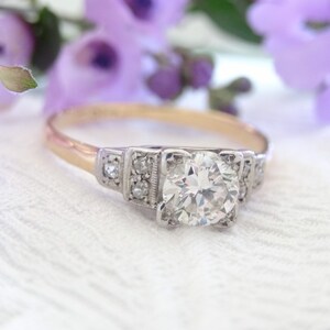 May include: A vintage engagement ring with a large, round, brilliant-cut diamond set in a platinum band. The ring has a delicate, Art Deco-inspired design with small diamonds on the sides.