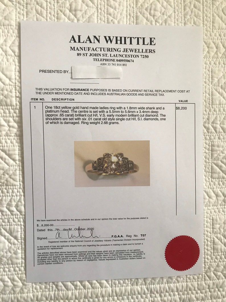 May include: A yellow gold ladies ring with a platinum head. The center of the ring has a large, brilliant cut diamond. The shoulders of the ring are set with six smaller diamonds. The ring weighs 2.68 grams.  F.G.A.A. Reg No. T07