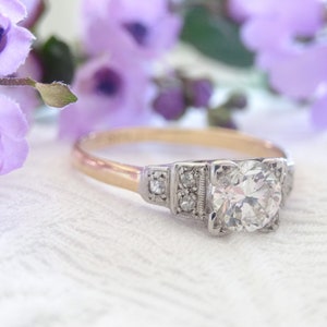 May include: A vintage engagement ring with a large, round, brilliant-cut diamond set in a platinum setting. The band is yellow gold.