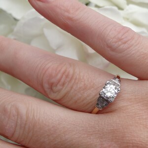 May include: A gold band engagement ring with a large, round, clear diamond center stone and smaller diamonds on the band.