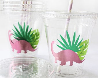 May include: Clear plastic cups with pink dinosaur and green leaf designs. Each cup has a matching lid and a striped straw. The cups are suitable for a party or event.