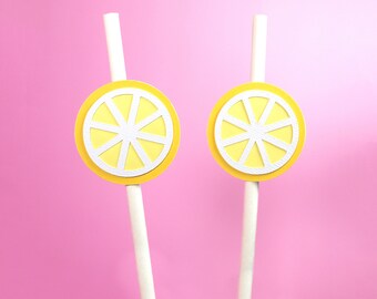 May include: Two white paper straws with yellow lemon slice cutouts attached to the top. The lemon slices have a white center with a white outline.