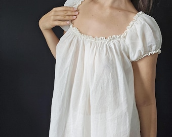 May include: A white cotton peasant top with a gathered neckline and short puffed sleeves.