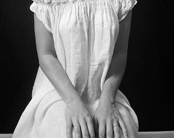 May include: A white off-the-shoulder dress with a ruffled neckline. The dress is made of a lightweight fabric and has a flowing silhouette.